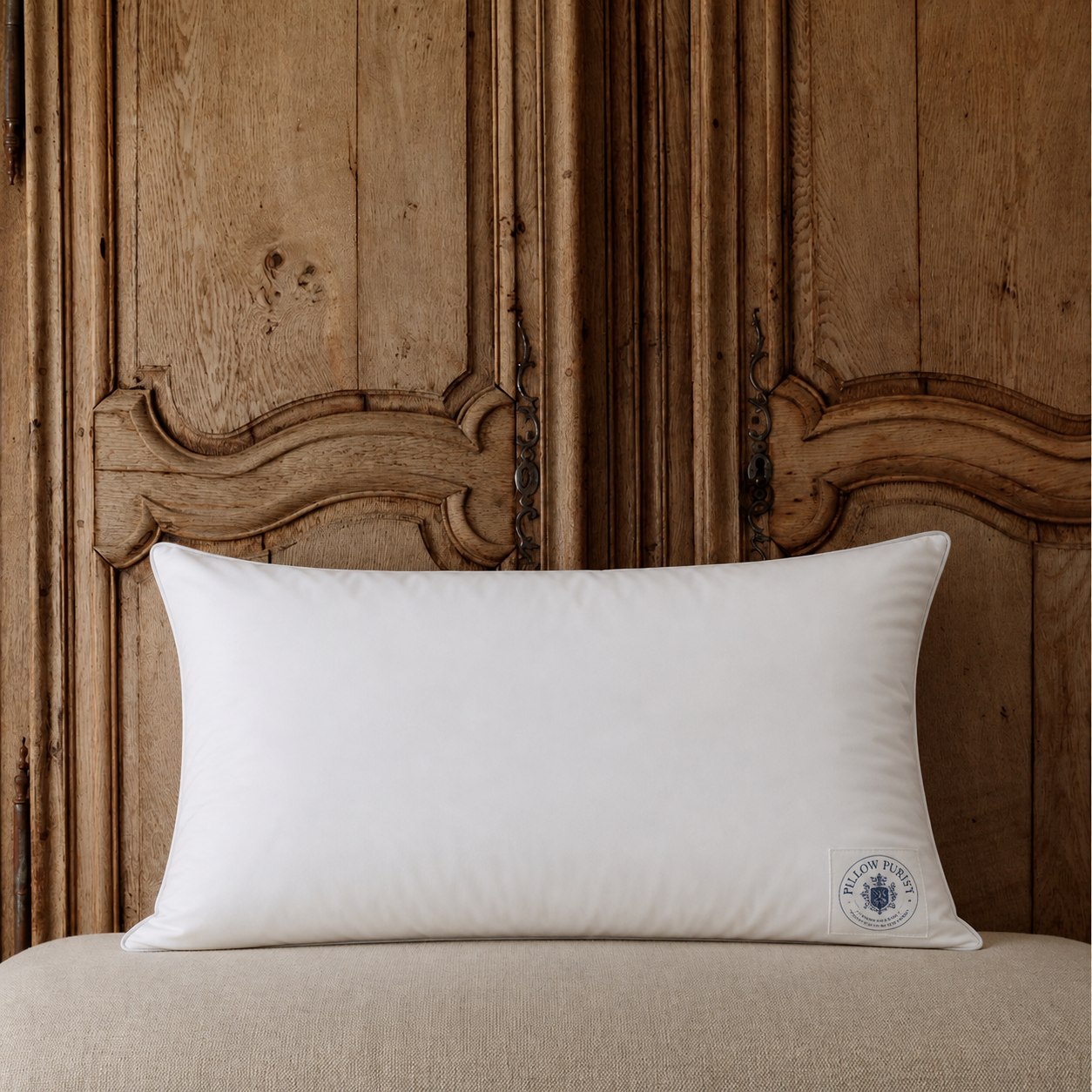 The Pillow Purist Signature Pillow against antique French oak headboard